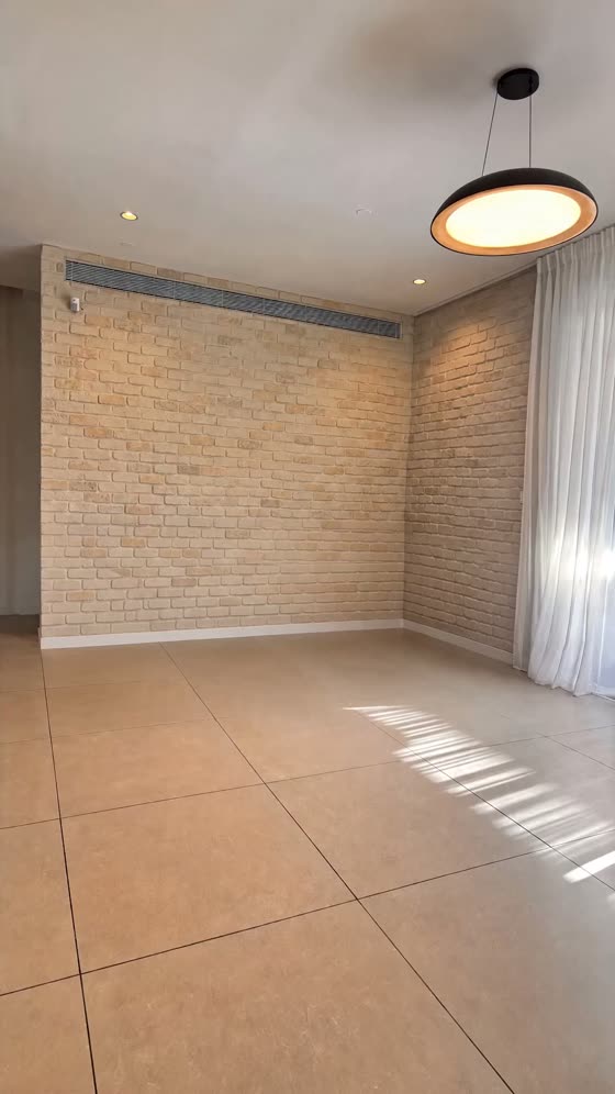הסלון לפני: חדר ריק לגמרי, קיר לבנים, וילון ותקרה