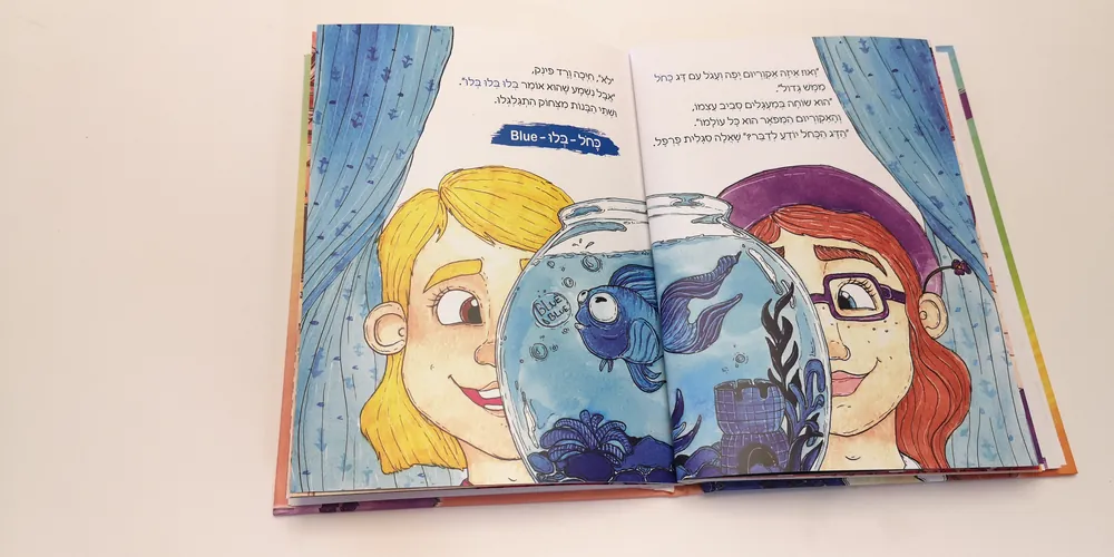 הספר סגלית והצבעים באנגלית פתוח בעמוד של הדג הכחול באקווריום